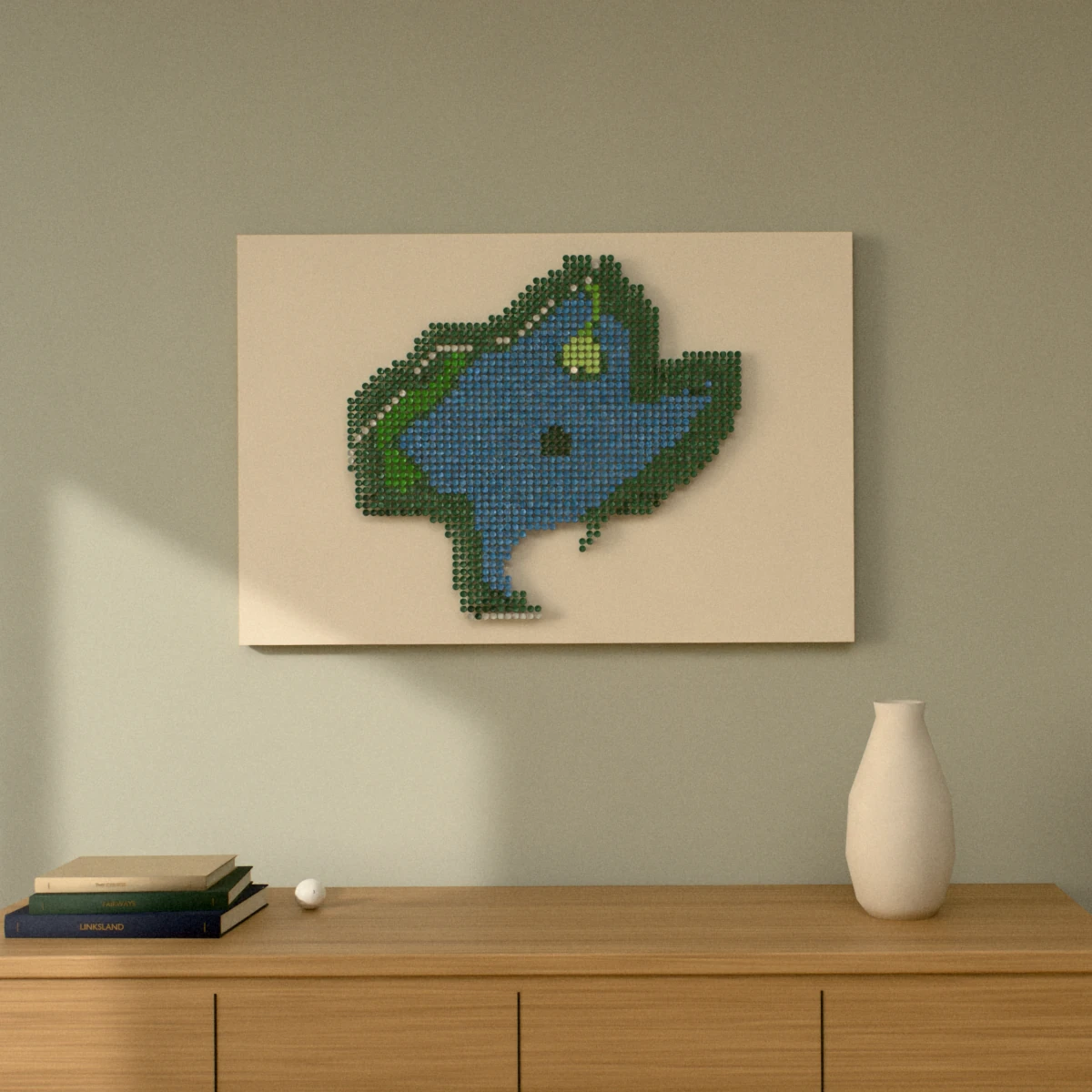 A golf-tee picture of a par 3 with a green surrounded by water, hung wide on a sage wall above a wooden sideboard with books and a vase.