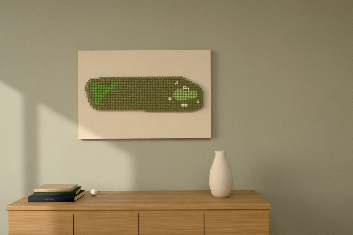 A golf-tee picture of a short par 3 on a links course, hung wide on a sage wall above a wooden sideboard with books and a vase.